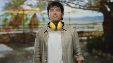 Kulaklık takan İspanyol bir adam restoran terasında manzaralı bir jest yapıyor..