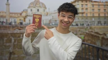 Beyaz kazak giyen ve elinde pasaport olan bir adam Roma binasını işaret ediyor. Seyahat macerası..