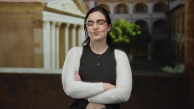 Roma harabeleri önünde kollarını kavuşturmuş bir kadın, tarihi geçmiş ve modern tarzın bir karışımını sergiliyor..