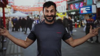 İspanyol asıllı sakallı bir adam renkli bayraklarla dolu kalabalık bir caddede şakacı hareketler yapıyor. Gün içinde açık hava sahnesinde bulanık kalabalıkla çevrili..