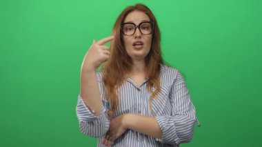 Yeşil stüdyoda uzun kollu çizgili gömlek giyen beyaz kadın parmak uçlarına kadar yeşil stüdyoda; kendine güven.