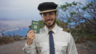 Pilot üniformalı genç adam, Güney Kore pasaportunu bir plaj zemininde tutuyor. Uluslararası seyahat ve havacılık temalarını açık havada gülümseyerek sergiliyor..