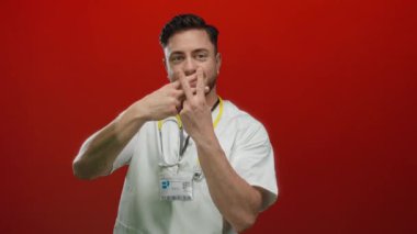 Genç doktor, steteskop takmış hashtag 'i işaret ediyor ve canlı kırmızı bir arka plana gülümsüyor..