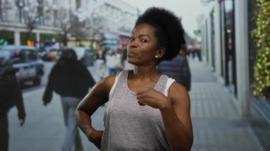 Yoğun bir şehir caddesinde güvenli bir şekilde poz veren kadın, insanlar ve araçlarla çevrili, canlı bir şehir yaşam tarzı ifade eden, canlı bir açık hava ortamında çeşitlilik gösteren.