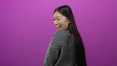 Uzun saçlı, rahat süveter giymiş, pembe arka planda gülümseyen bir kadın kendine güvenini ve pozitifliğini belli ediyor..