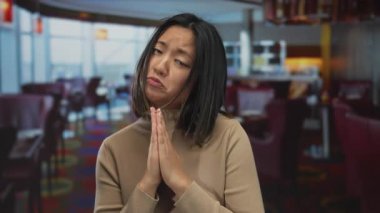 Restoranda elleri renkli mobilyalarla birbirine kenetlenmiş duygularını ifade eden bir kadın anlamlı ya da içten bir istek ya da minnettarlık hissi veriyor..