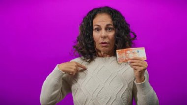 Bir kadının elinde Filipinli bir peso banknotla münferit bir mor arka plana bakması şaşkınlık ve merakını dile getiriyor..