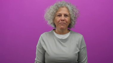 Kıvırcık gri saçlı kadın canlı pembe bir duvara karşı neşeli yüzler sergiliyor ve enerjiyi ve duyguları yakalıyor..