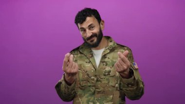 Askeri üniformalı İspanyol bir adam iki eliyle canlı pembe bir arka plana karşı para hareketi yapıyor..