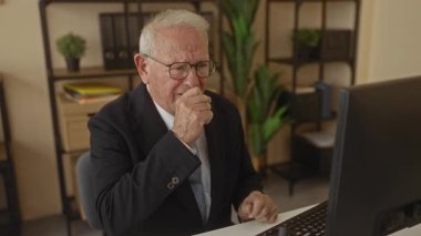 Takım elbiseli kıdemli bir adam ofis masasında otururken boğaza dokunurken ve bilgisayarın başında öksürürken iç mekanda iş ortamını hazırlarken rahatsız görünüyor.