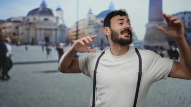 Sakallı İspanyol bir adam, açık havada gülümsüyor, sokak ortamında beyaz gömlek giyiyor, bulanık tarihi mimariye karşı canlı bir etkileşim içinde.