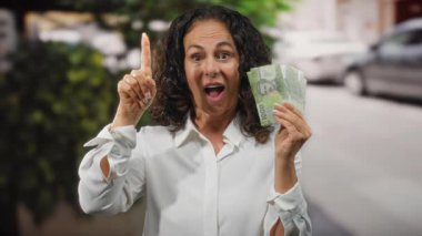 Şehirde elinde neşeli bir ifadeyle Şili pezosu tutan bir kadın bir fikri işaret ediyor..