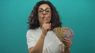 Meksika pezosu tutan kadın yeşil arka planda sessiz jest yapıyor..