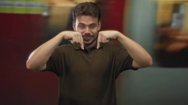 Adam her iki işaret parmağı aşağı tren istasyonu platformu, aşağıdaki uzaya gülümseme ve jest; dostça davet.