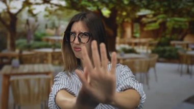 Gözlüklü İspanyol kadın açık hava restoranının terasında avuç içlerini gösteriyor..