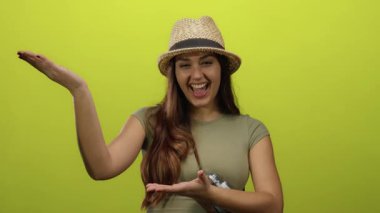 İspanyol kadın şapkalı, gülümseyen ve elleri ile parlak sarı bir arka plana doğru hareket eden davetkar ve neşeli bir sunum sunuyor..