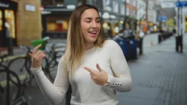 Canlı bir şehir caddesinde neşeli bir şekilde dans eden genç bir kadın bulanık arka planda, açık havada mutluluk ve enerji ifade ediyor..