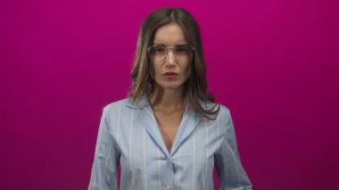 Gözlüklü bir kadın pembe stüdyoda açık elle yumruk atıyor, kararlılık odaklı..