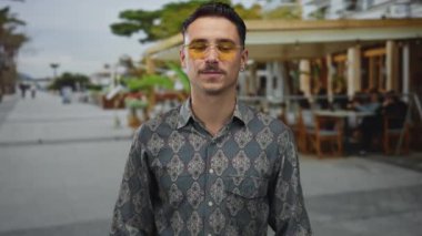 Genç İspanyol adam kalp hareketi yapıyor ve teras caddesindeki bir açık kahve restoranında öpücük yolluyor..