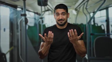 Yakışıklı, sakallı bir genç, otobüsün içinde kafası karışmış, etrafı boş koltuk ve direklerle çevrili, siyah gömlek giymiş, kapalı bir toplu taşıma seti içinde etkileyici görünüyor..