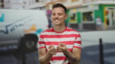 Şehir sokaklarında kırmızı çizgili tişört giyen, kendine güvenen ve çekici görünen genç bir adam..