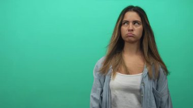 Nane yeşili duvarlı, beyaz kolsuz bluz ve kot gömlekli bir kadın yüzü somurtuyor ve yuvarlanan gözler stüdyoda..