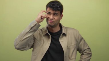 Adam stüdyoda yüzünü çimdiklerken, adam yeşil gömlekli genç bir İspanyol gibi görünüyor ve kafası karışıyor..