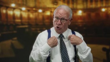 Takım elbiseli kıdemli bir adam, loş bir kilisede konuşurken güven içinde el hareketleriyle puanlarını vurgulayarak otorite ve bilgelik duygusu yaratıyor..