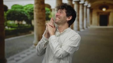 Elinde tabancayla gezen İspanyol adam üniversite kampüsündeki sütunlu Roma Anıtı 'nda poz veriyor.