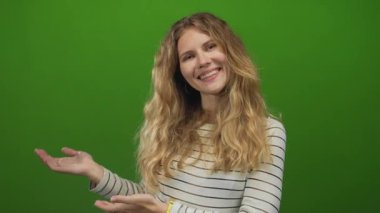 Stüdyo sahnesini sunan kadın, çizgili gömlek giyerken yeşil arka planda neşeyle gülümseyen genç sarışını anlatıyor..