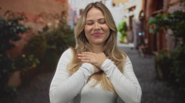 Beyaz elbiseli sarışın kadın kaldırım taşlı sokakta el ele tutuşuyor. Minnettarlık, samimiyet, minnettarlık..