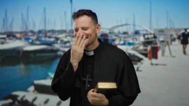 Papaz kılığında bir adam elinde İncil 'le marinada arka planda teknelerle kılık değiştirip deniz kenarında tefekkür ve neşe içinde..