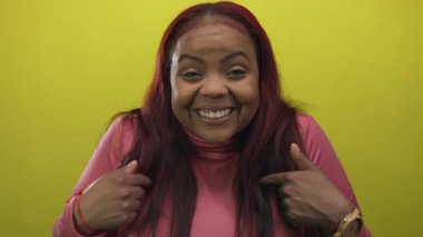 Yakın plan kadın geniş bir gülümseme ve kendini gösteren parlak sarı bir stüdyo; güven güçlendirici başarı.