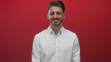 İspanyol adam yüzü göz kırpan dişlek gülümseme ve kendine güvenen bakışlar kırmızı stüdyo beyaz gömlek giyen; neşeli neşeli cazibeli.