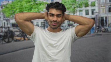 Güneşli şehir sokağında başı arkasında elleri olan adam bisiklet ve ağaçlarla dolu; huzur dolu yalnızlık..