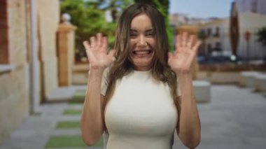 Güneş ışığıyla aydınlanan kaldırım taşı caddesinde el sallayan kadın, sevinç kutlamaları tezahüratı.