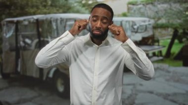 Genç Afrikalı Amerikalı adam parmaklarıyla kulaklarını tıkadı ve park halindeki arabanın yanındaki beyaz gömlekle dillerini dışarı çıkardı..