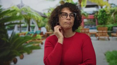 Havuz başında diş ağrısı için elleri yanağında kırmızı kazak giyen bir kadın..