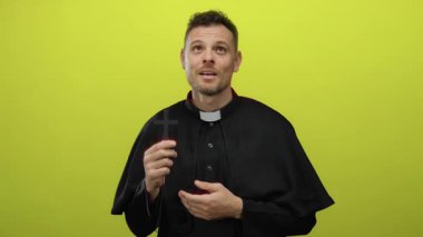 Papazın parlak sarı arka plana karşı haç tutması ciddi bir ifadeyle manevi bağlılık gösteriyor.