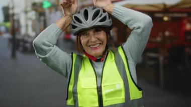 Kıdemli İspanyol kasklı bir kadın şehir sokaklarında eğlenmek için poz veriyor hareketli şehir manzarası güvenlik bağlamında canlı bir ifade yakalanıyor.