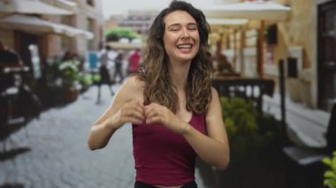 Pembe tişörtlü genç İspanyol kadın güneş ışığı altında kısık sesle gülümsüyor. Mutluluk merakı..