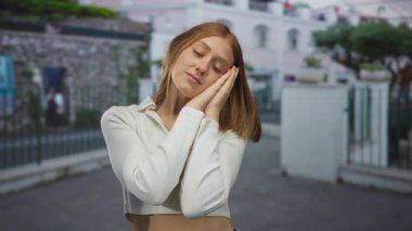 Sarışın genç bir kadın kentin sokaklarında uyku jesti için yanaktan yanağa dinleniyor. Huzur içinde yat..