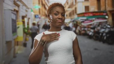 Genç Afrikalı Amerikalı kadın, hareketli bir şehir caddesinde dururken altın bir kolyeyi işaret ediyor..