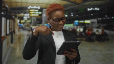 Genç gülümseyen Afrikalı Amerikalı kadın havaalanı terminalinden tablet alıyor; dostça bir davet..