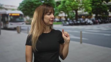 Kadın, otobüsün ve kaldırımın yanındaki bir caddede sağı işaret ediyor; kendine güvenen şehir hayatı..