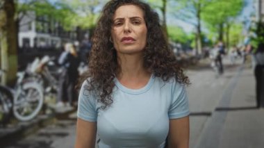 Şehir caddesinde duran İspanyol kadın gün ışığında park halindeki bisikletlerle ortaya çıkıyor..