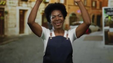 Önlükle gülümseyen kadın şehir sokaklarında neşeyle dans ediyor, şehir yaşamını ve dışarıdaki mutluluğu somutlaştırıyor..