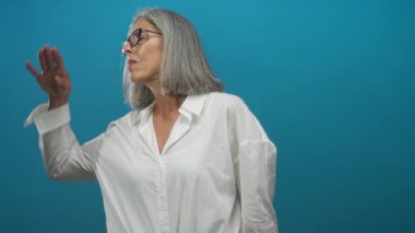 Stüdyoda göğüs göğüse gözlüklü bir kadın gök mavisi arka plana karşı koruyucu gözler takıyor; sakin yansıma.