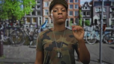 Kamuflaj üniformalı kadın asker, şehir caddesinde kulağı kulaklarında künye takıyor, disiplin görevine hazır..