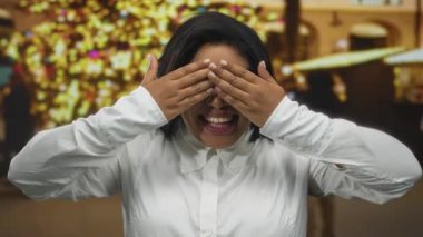 Gözlüklü ve beyaz gömlekli kadın şehir ışıklarına karşı gülümsüyor, canlı bir şehir ortamında mutluluk ve neşe saçıyor..